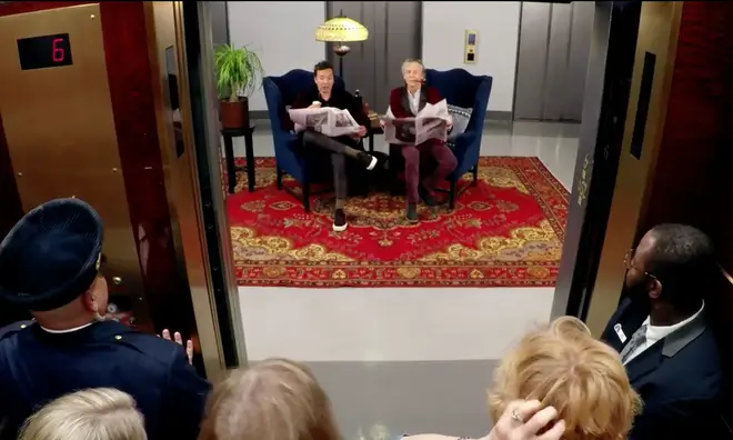 The video starts with the pair sitting in armchairs and reading newspapers, when the lift doors open 'at the wrong floor' in front of them.